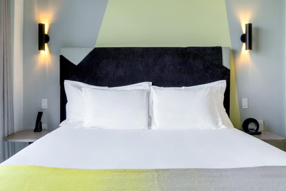Drift off on crisp linens beneath stylish, modern headboard lighting.