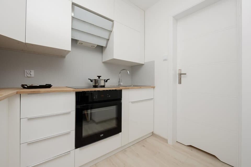 A sleek white kitchen with modern appliances, minimalist storage, and a clean, streamlined aesthetic.

