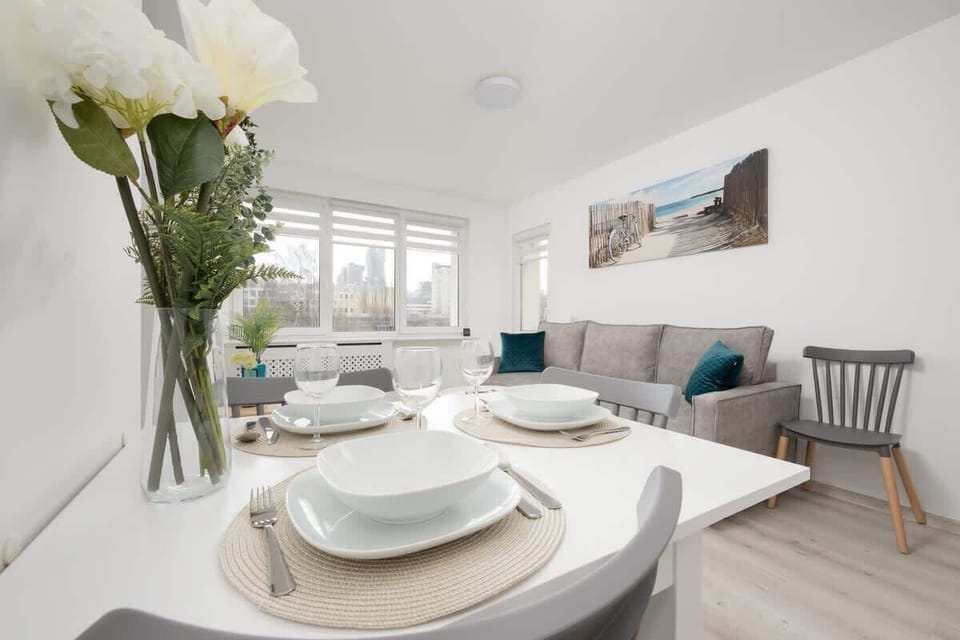 A close-up of a beautifully set dining table with fresh flowers, elegant dishware, and a bright, airy ambiance.

