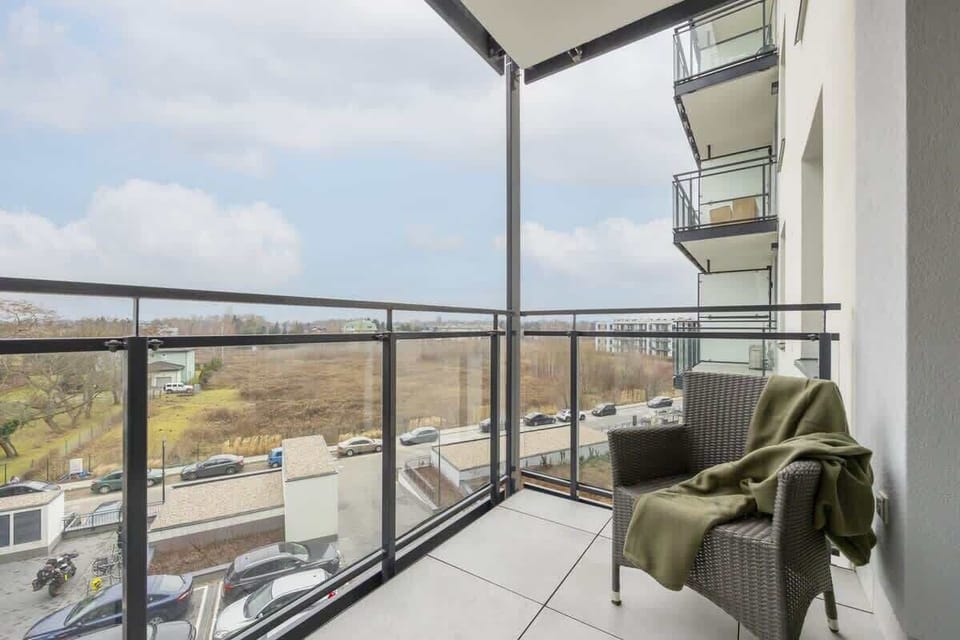 A private balcony with a glass railing and a scenic view of the surrounding area, offering a peaceful spot to relax.

