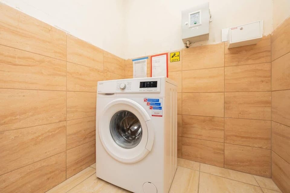 A laundry area featuring a washing machine, warm wooden wall tiles, and a well-organized, compact design for convenience.

