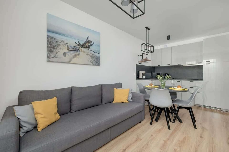 Another angle of the main living space, featuring a cozy gray sofa, a stylish dining table, and a modern industrial-style pendant light.

