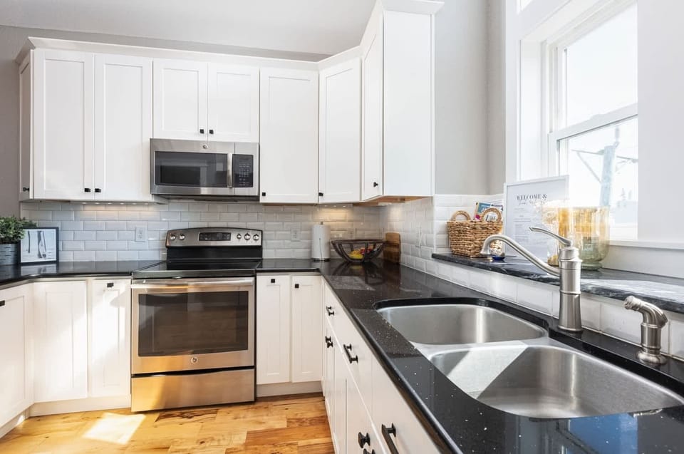 Modern Coastal Kitchen w/ Stainless Steel Refrigerator, Electric Range, Microwave, Sink, Dishwasher, Cooking Utensils, and Kitchen Bar Chairs