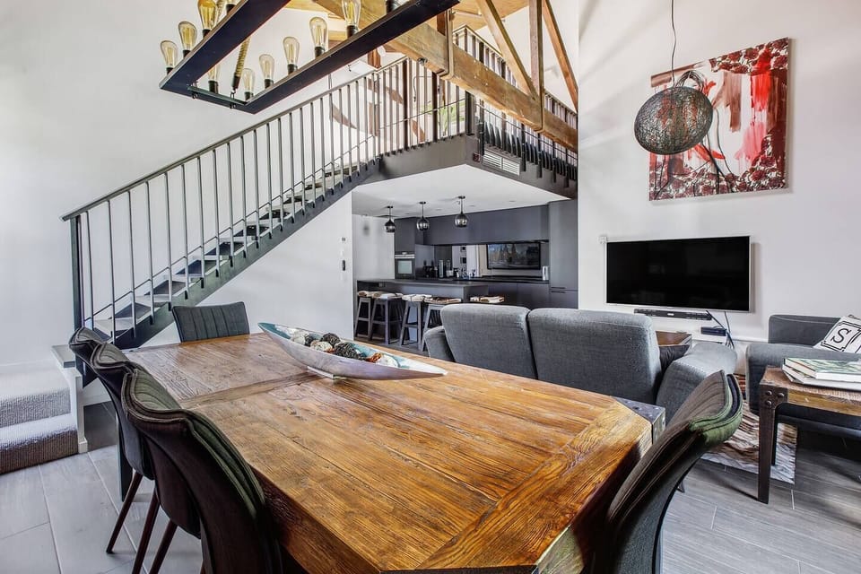 The apartment gives off a majestic vibe with soaring ceilings and a grand staircase leading up to the second level.