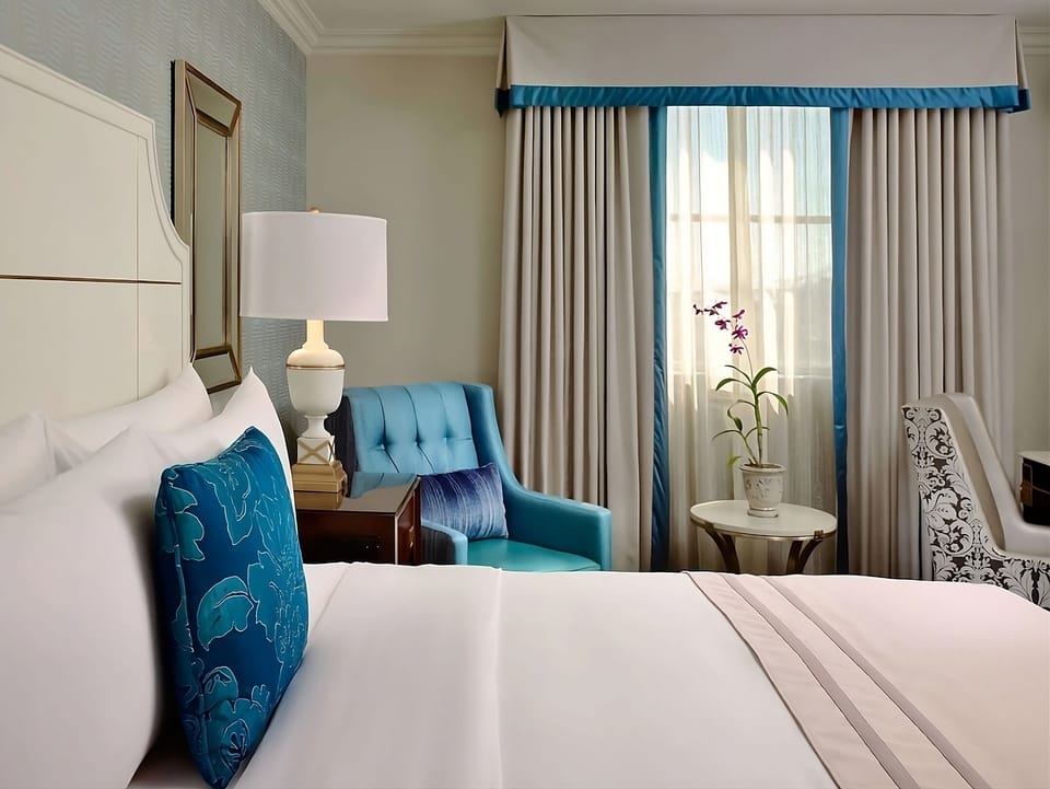 Sink into crisp linens beside a cozy reading chair.