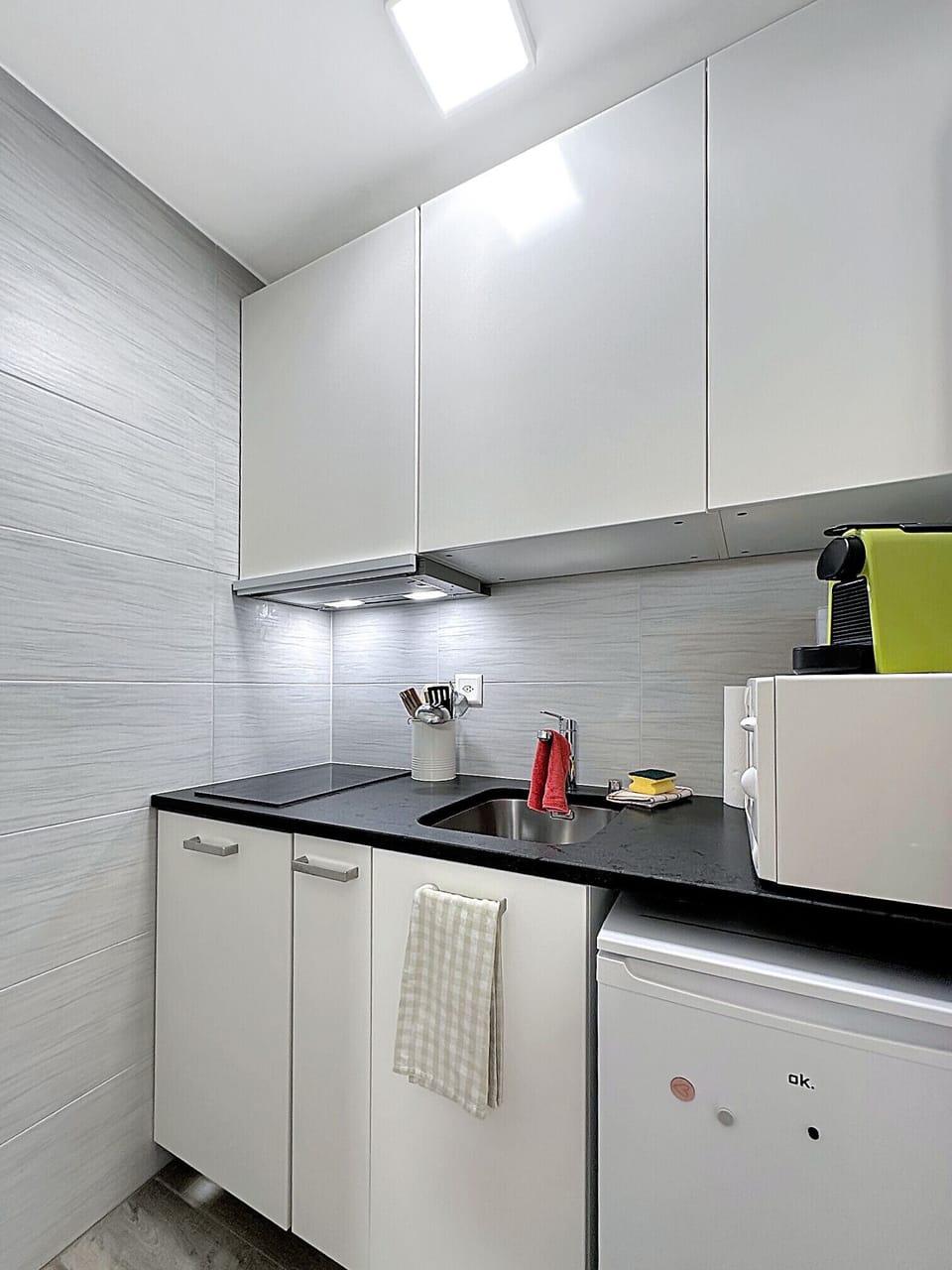 Kitchen with coffee machine, microwave and functional storage units.