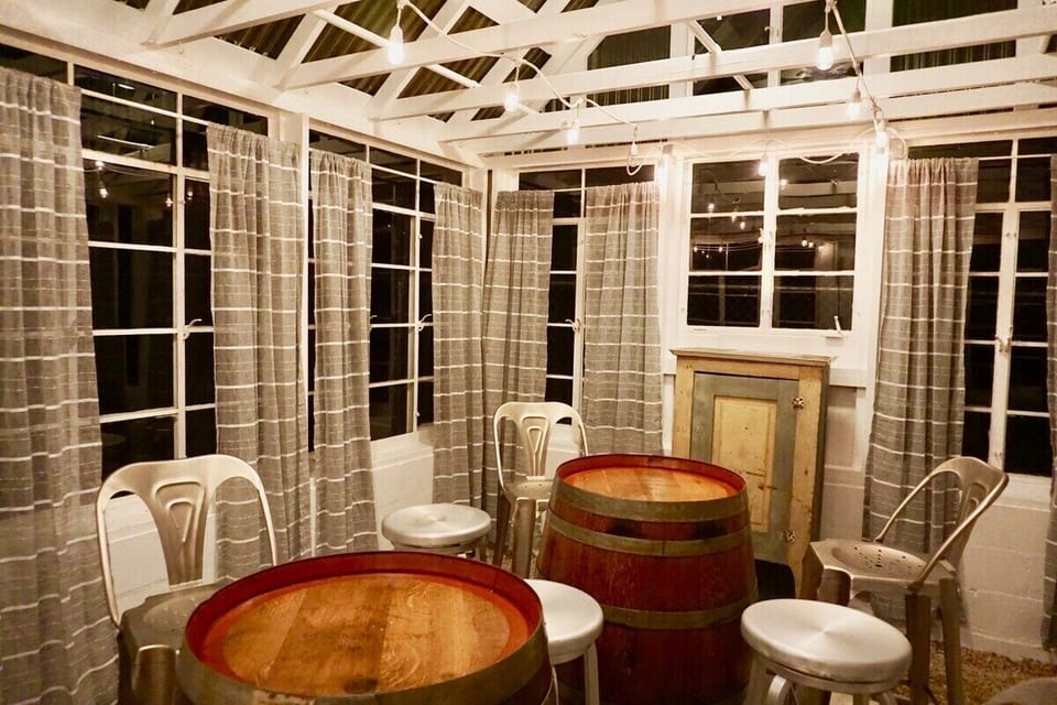 Dine under the stars in the enchanting greenhouse, where a cozy table for six awaits amidst twinkling lights and lush greenery