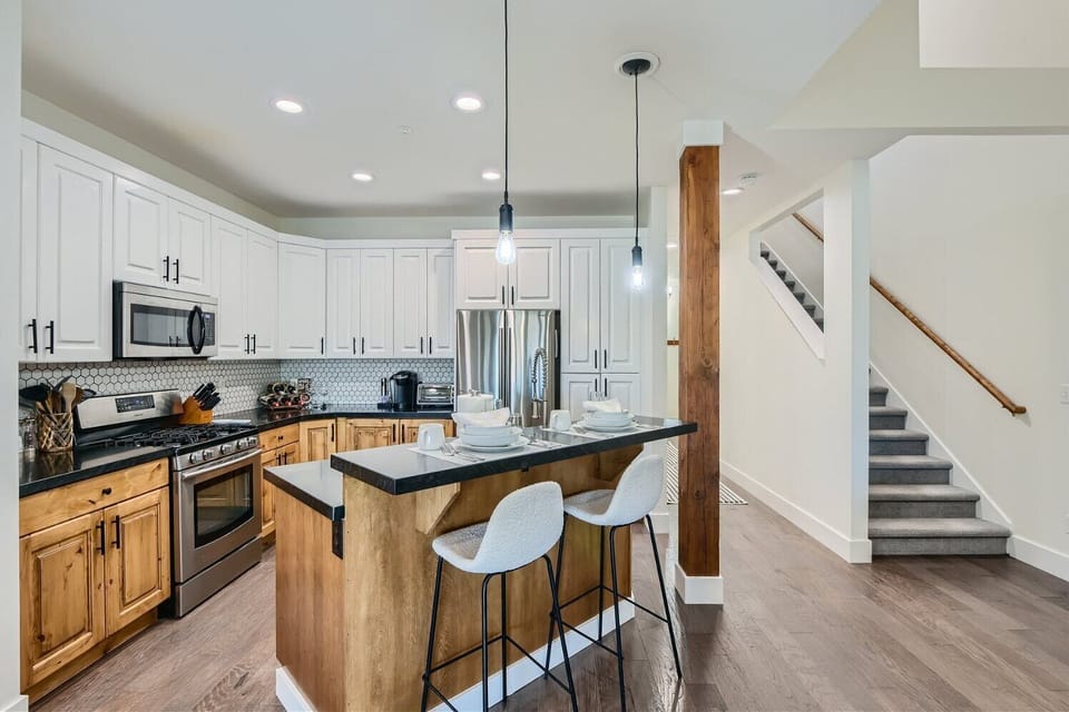 Prepare meals in our fully equipped kitchen, featuring a large island with bar seating, modern stainless steel appliances, and a stylish two-tone design. All the essentials for a great stay.