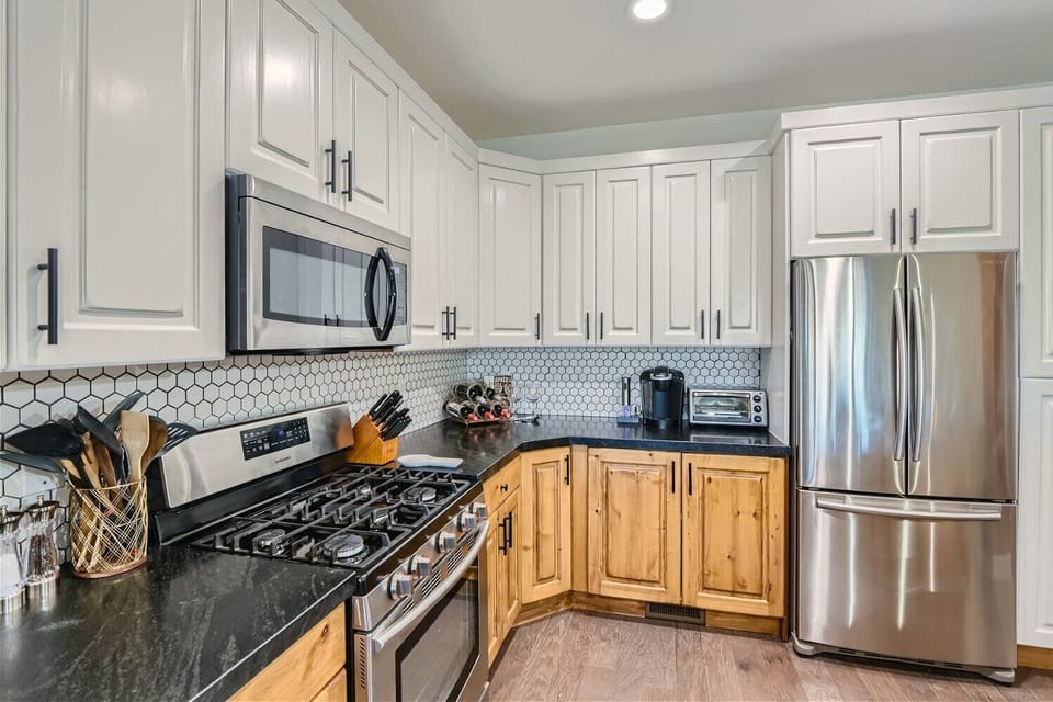 Cook meals in our fully equipped kitchen, featuring modern stainless steel appliances, dark countertops, and stylish two-tone cabinetry. All the essentials for a great stay.