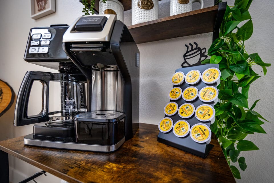 Coffee station with pod rack, machine, and cozy café-style wall art.