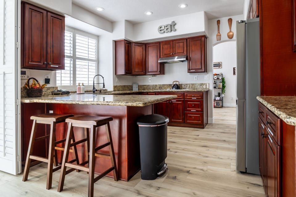 Modern kitchen with island seating, wood cabinets, and natural light.