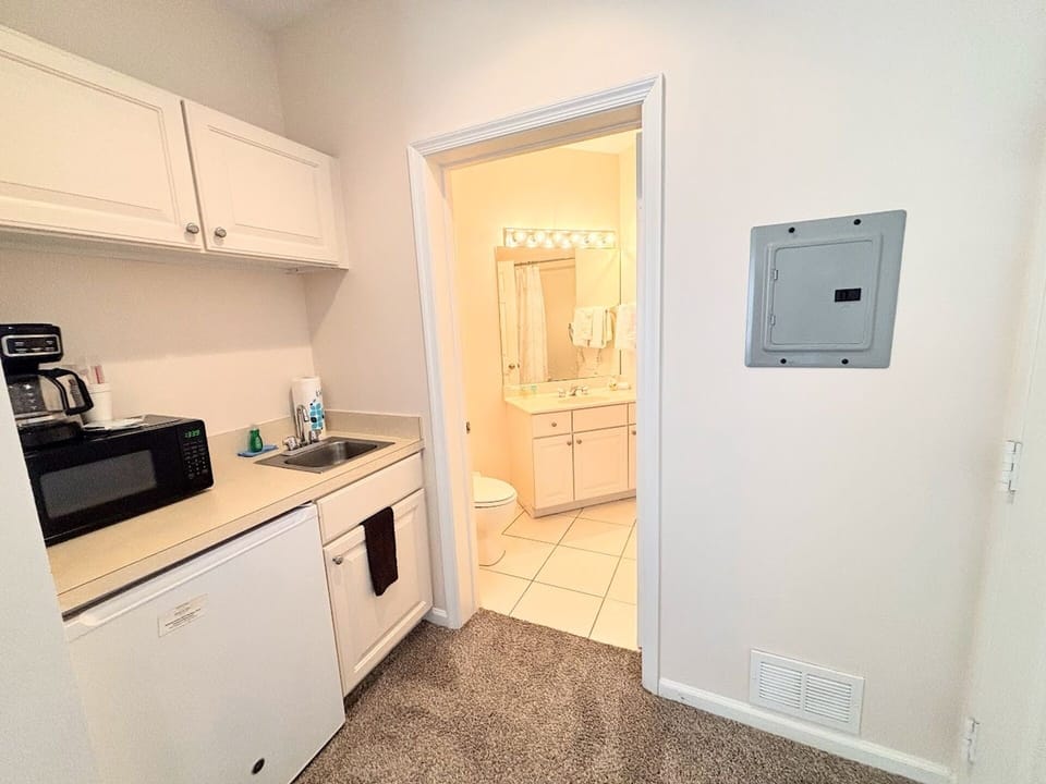 Convenient kitchenette area with microwave, mini fridge, sink, and easy access to the bathroom.