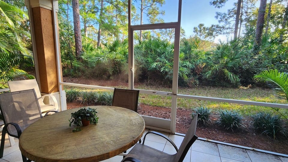 Private screened patio with outdoor seating and peaceful views of the surrounding landscaping.