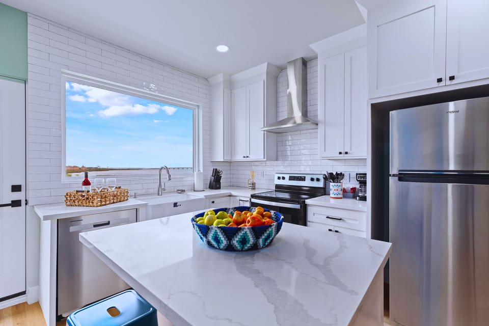The modern chef’s kitchen showcases a spacious waterfall island and upscale designer finishes. Fully stocked with premium appliances and essentials, it’s perfect for creating gourmet meals or whipping up simple snacks with ease.