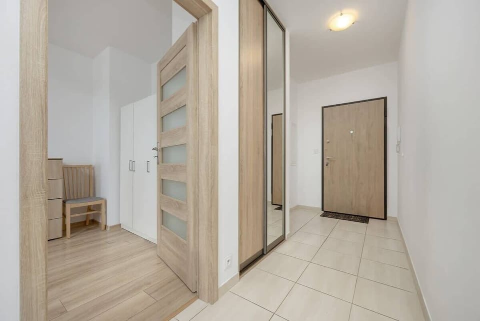 A spacious hallway with built-in wardrobes, wooden doors, and tiled flooring, offering plenty of storage and an organized entrance area.

