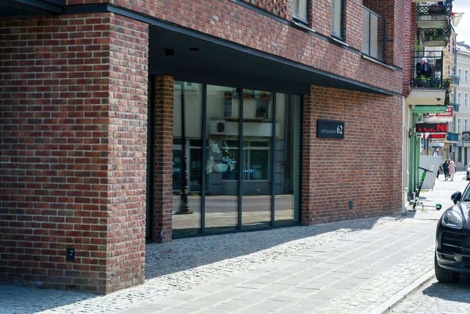 The entrance to a modern brick apartment building, featuring large glass doors and a stylish urban design.
