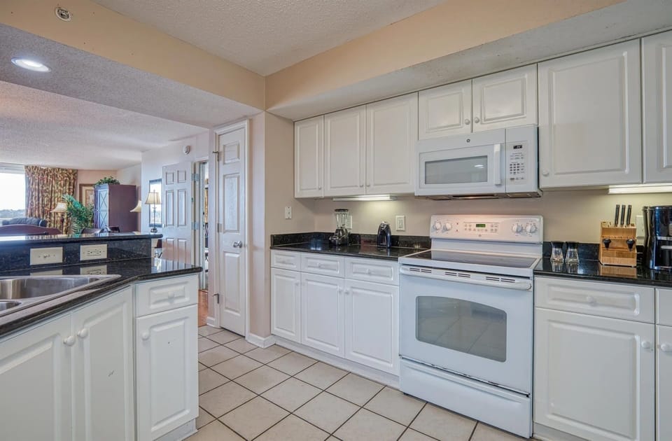 U-shaped kitchen with white appliances and tile