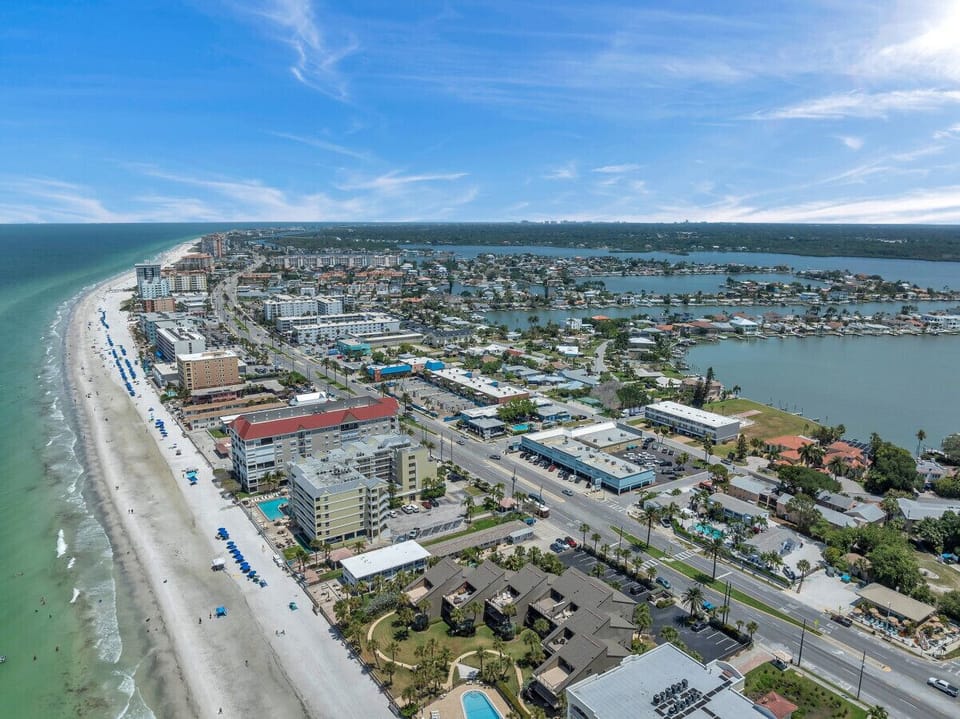 Aerial coastal view showcasing sandy beaches, blue water, and the surrounding area.
