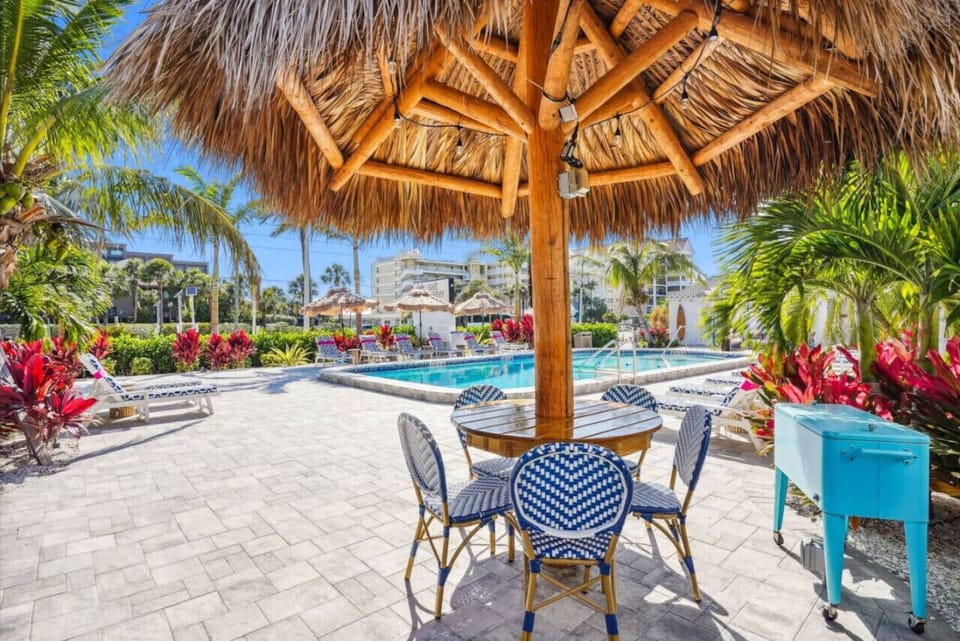 Covered outdoor seating area w/ tables & tropical touches, perfect for casual poolside hangouts.