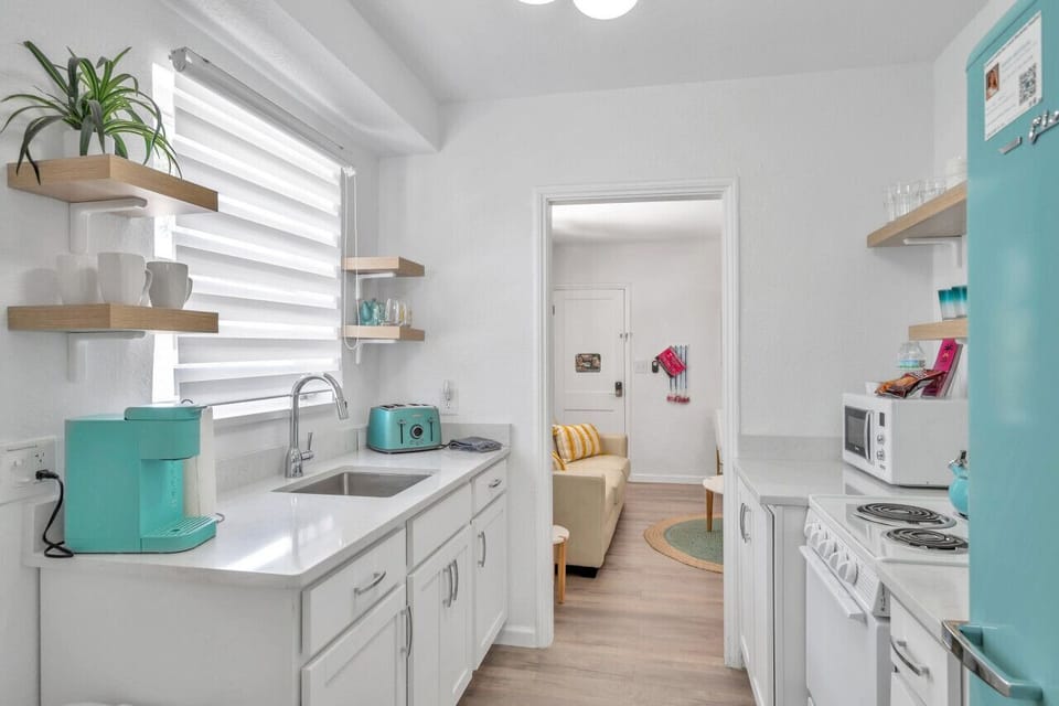 Fresh white kitchen w/ open shelves, ample counter space, and a light, welcoming vibe