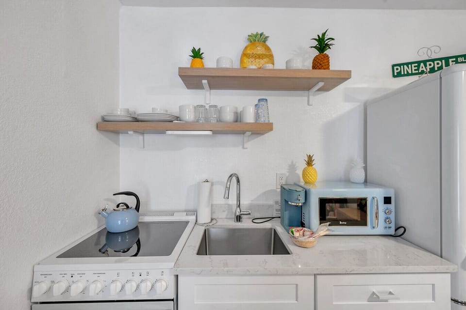 Well-organized kitchenette w/ open shelves, microwave, & cheerful tropical details.
