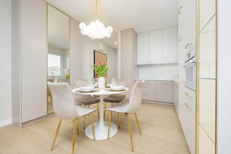A mirror-reflected view of the dining area, emphasizing the luxurious chandelier, elegant furniture, and built-in storage space.

