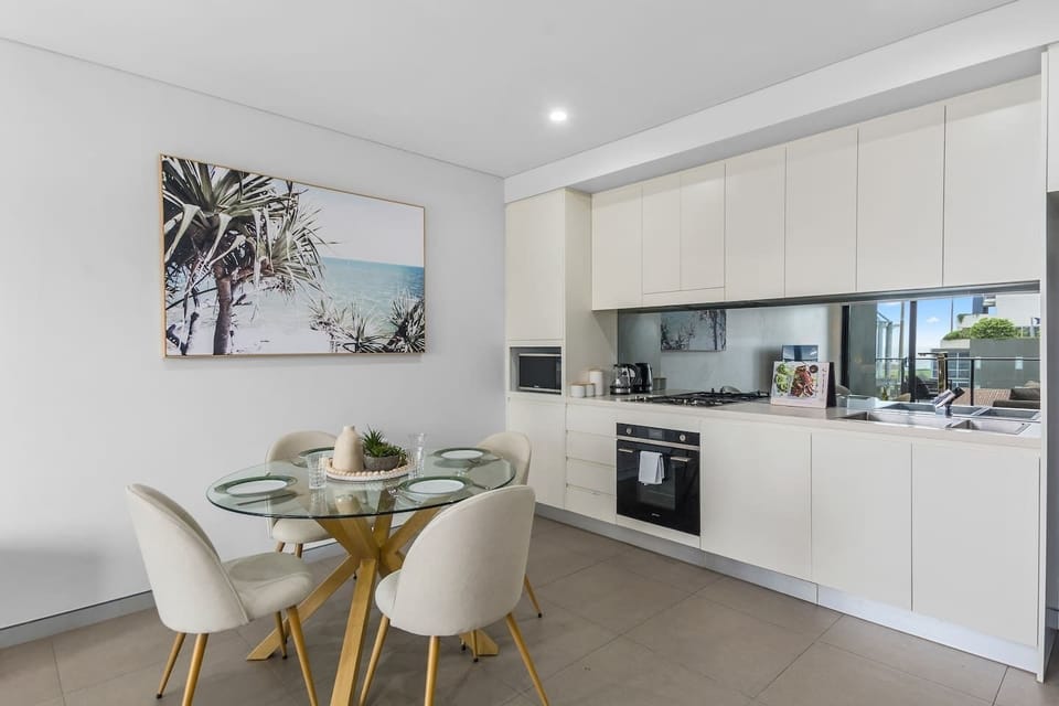 The streamlined kitchen enhances the open-plan dining and kitchen space featuring a long benchtop and large cabinets for ample storage. 
