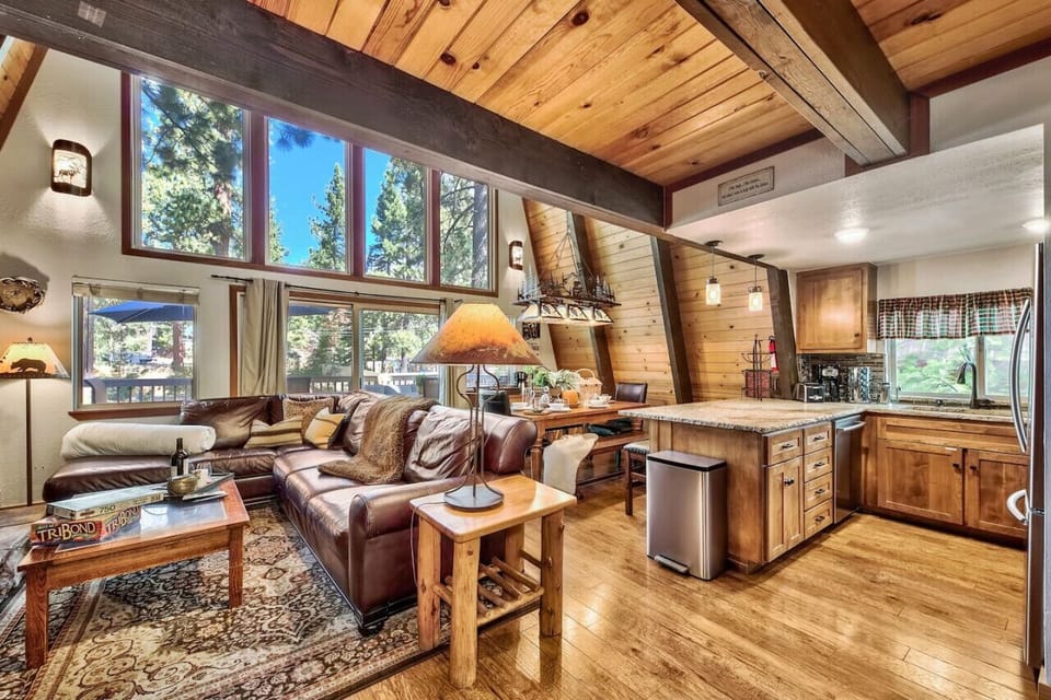 Open concept great room on main / mid level with sectional leather sofa, dining area, nicely appointed kitchen, large flat screen TV, wood burning fireplace and vaulted ceilings / windows.