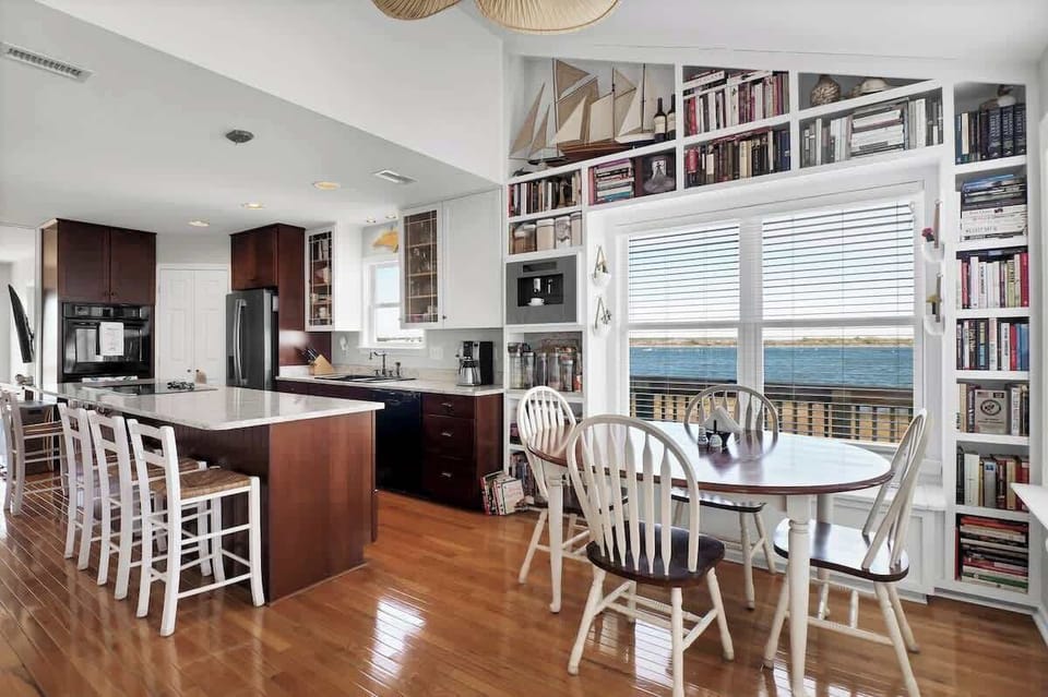 This bright and airy eat-in kitchen offers a cozy spot for meals with a view, surrounded by floor-to-ceiling windows that flood the space with natural light.