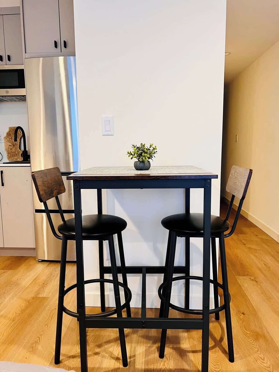 Cozy dining nook with modern bar seating, compact table, and warm wood floors in a bright, clean space.