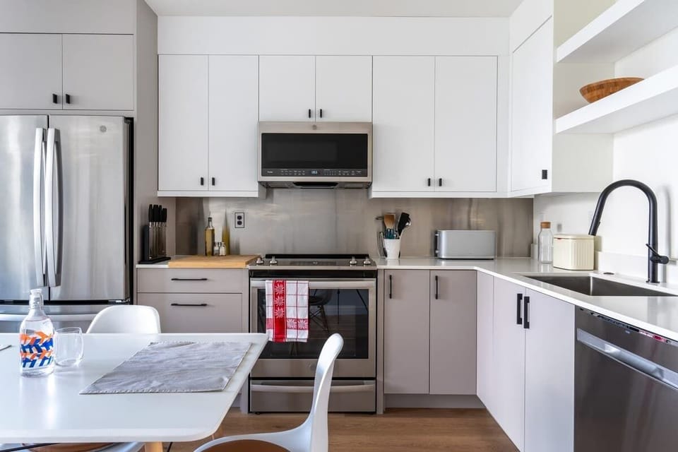 Bright, modern kitchen with sleek cabinetry, stainless steel appliances, open shelving, and a clean, functional layout.