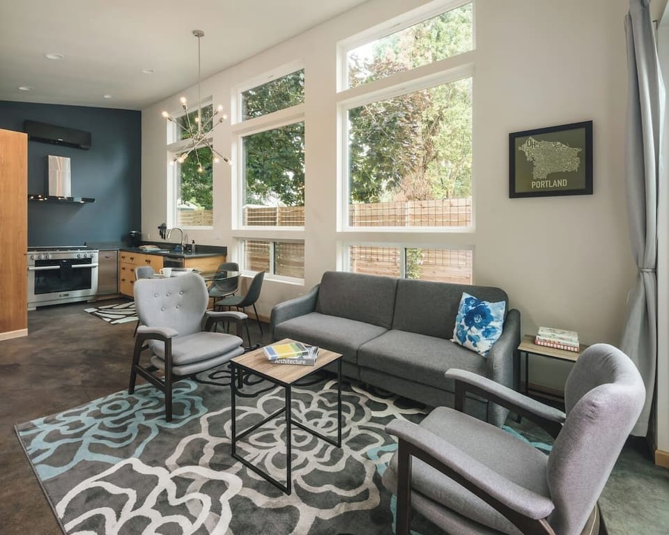 Living Room: Bright and stylish retreat with large windows overlooking lush greenery!