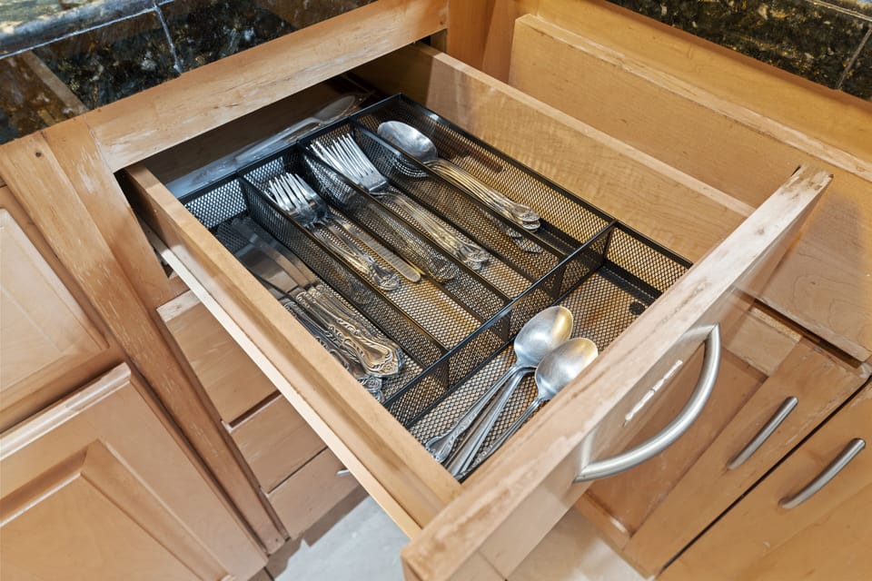 Silverware drawer: organized compartments, forks, spoons, knives.