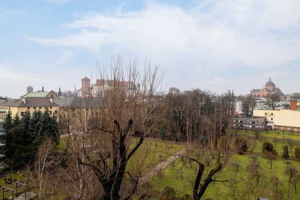 A picturesque view from the apartment window showcasing a historic building, lush greenery, and a distant church with a dome.

