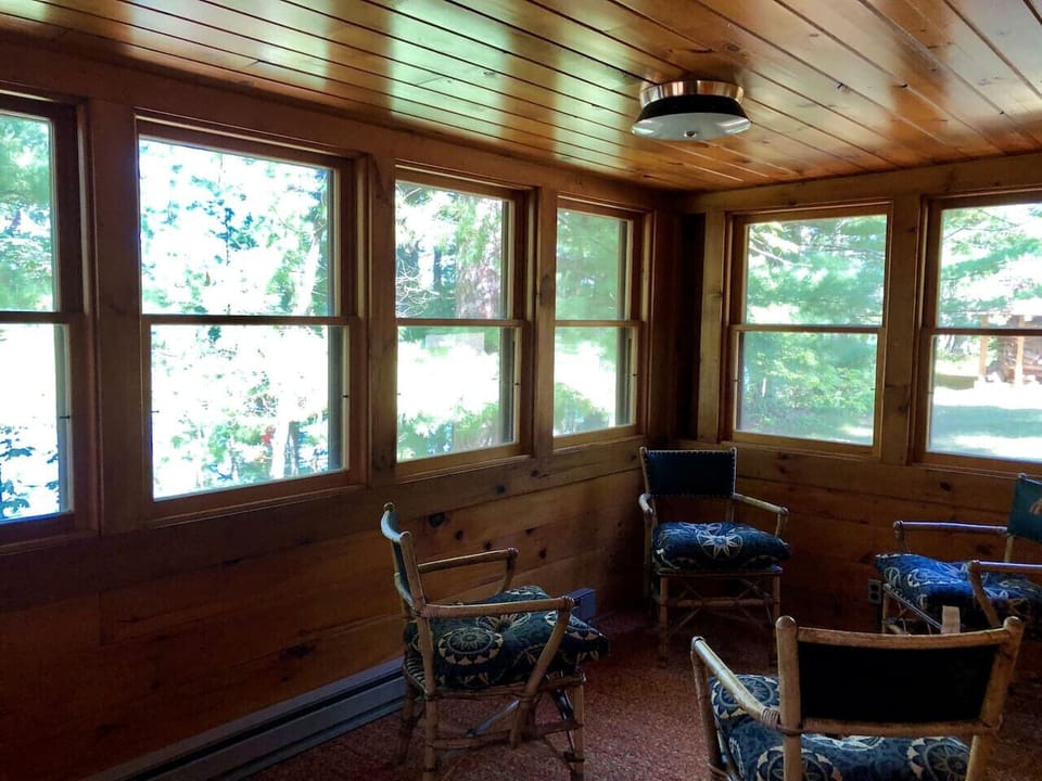 Cozy sunroom where you can unwind in comfortable seating while enjoying peaceful garden views through wraparound windows.