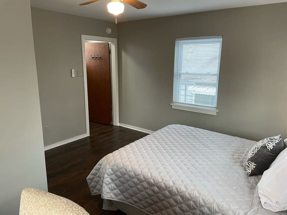 Bright bedroom with a cozy queen bed and hardwood floors.