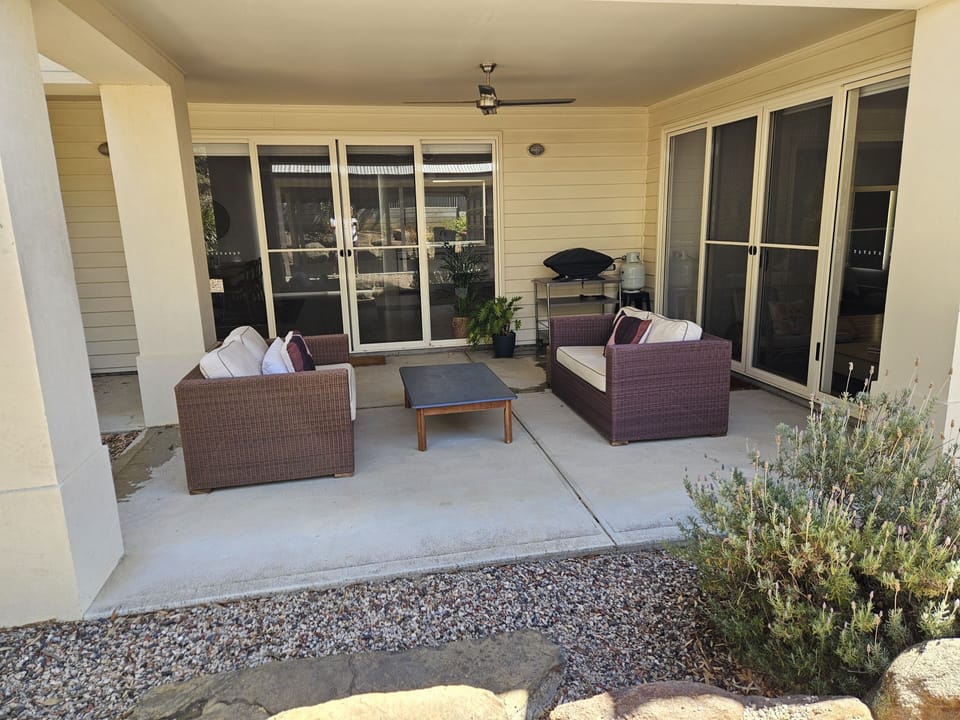 Outdoor undercover patio seats four people. Webber BBQ and table and chairs near