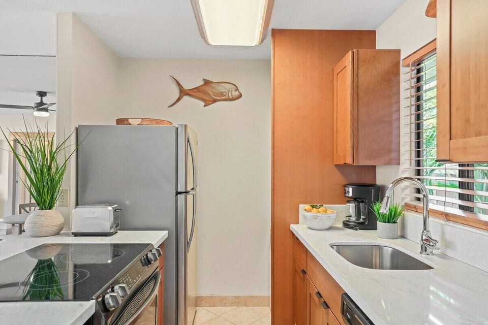 Kitchen with stainless steel appliances — wood cabinetry, island counter, and playful fish accent.