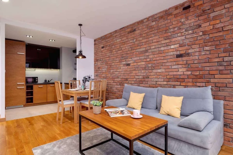Another perspective of the living space, highlighting the warm wooden flooring, exposed brick, and a stylish seating area.

