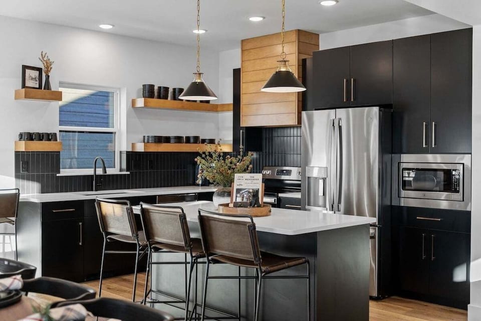 - Whip up snacks, meals, or cocktails in this modern and social kitchen
- Pull up a barstool and enjoy a chat while someone preps your favorite dish
- Bold black cabinetry pairs perfectly with wood accents and pendant lights