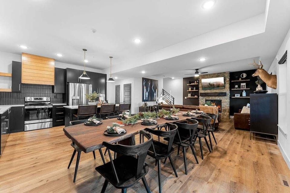 - Host big meals or casual breakfasts around the rustic live-edge table
- Modern black kitchen with wood accents is fully stocked and ready to go
- The open flow leads to a cozy lounge with fireplace and stylish touches