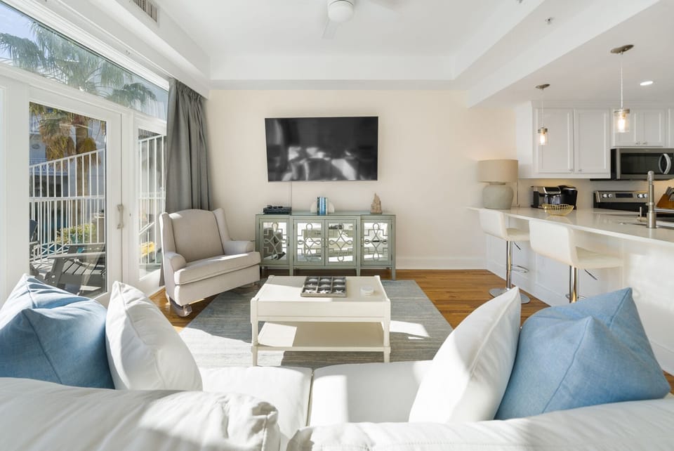 Relax in your bright, open living space with modern kitchen and peaceful balcony views through floor-to-ceiling windows.