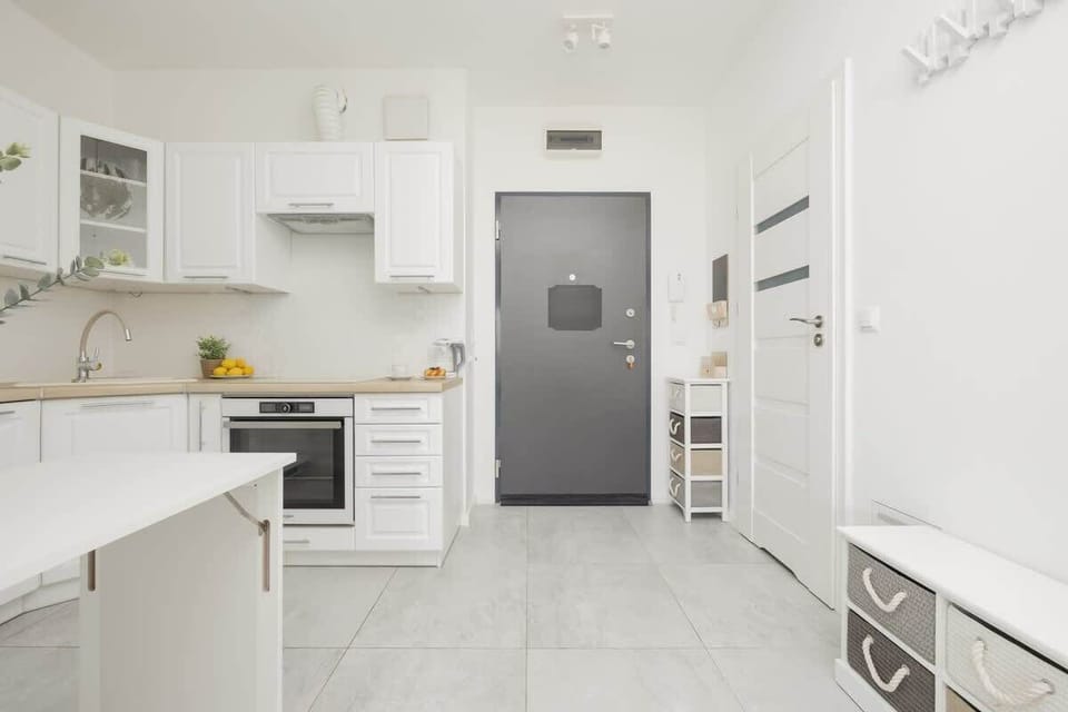 A modern, open kitchen connected to the entrance area, with white cabinetry and a well-organized layout.

