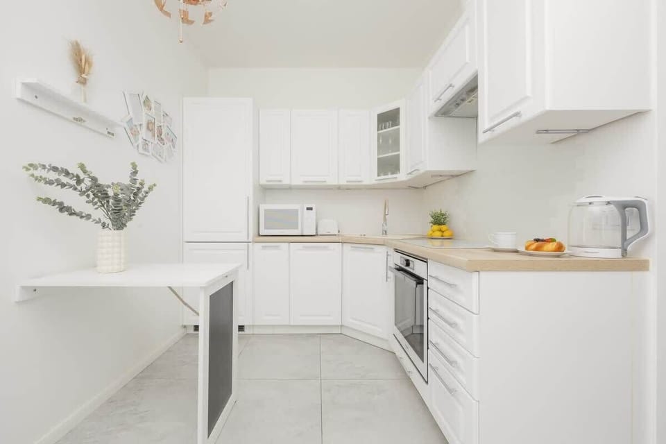 Another view of the kitchen, showcasing a decorative plant, a well-lit interior, and clean, contemporary finishes.

