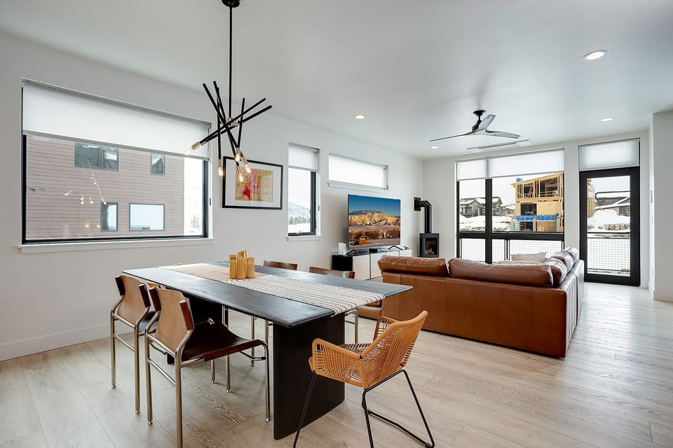 Unwind in your open-concept living space where modern elegance meets cozy comfort, featuring stunning mountain artwork and warm leather seating.