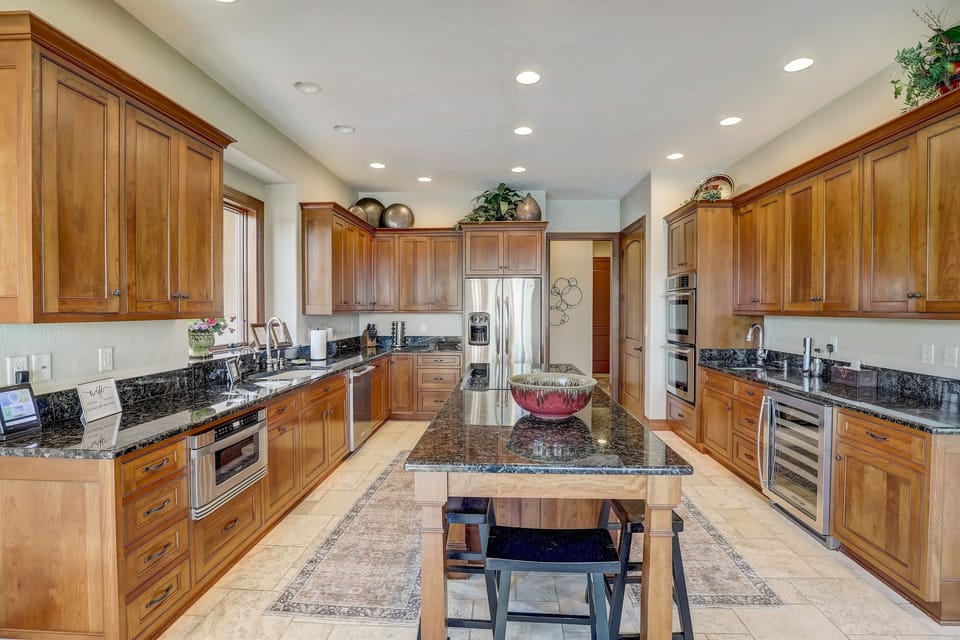 Spacious chef’s kitchen with granite countertops, stainless steel appliances, and large island, perfect for cooking and entertaining.