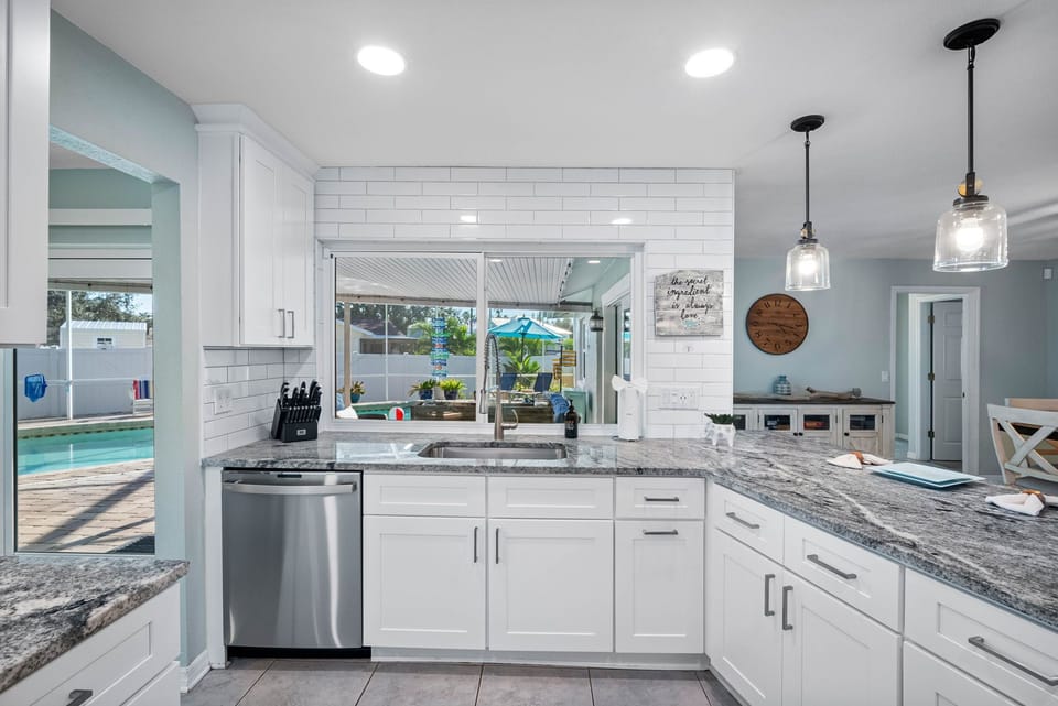 Sleek white cabinetry, stainless steel appliances, and granite countertops create a bright, elegant space for cooking and gathering.