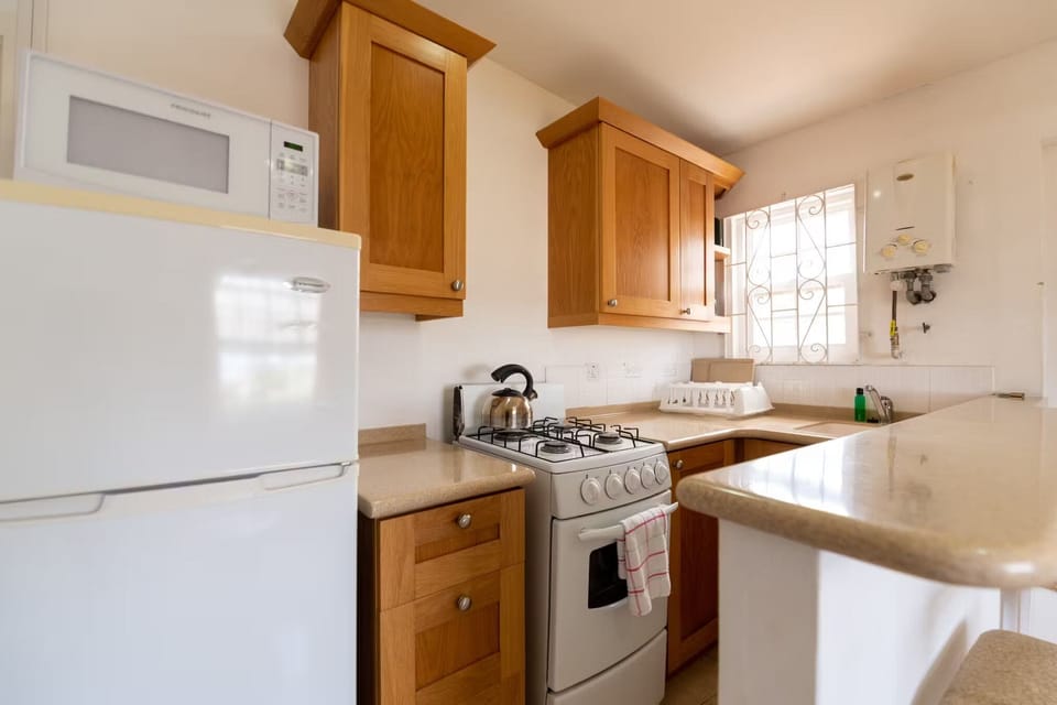 Cook comfortably with a full stove, fridge, and bright counters.