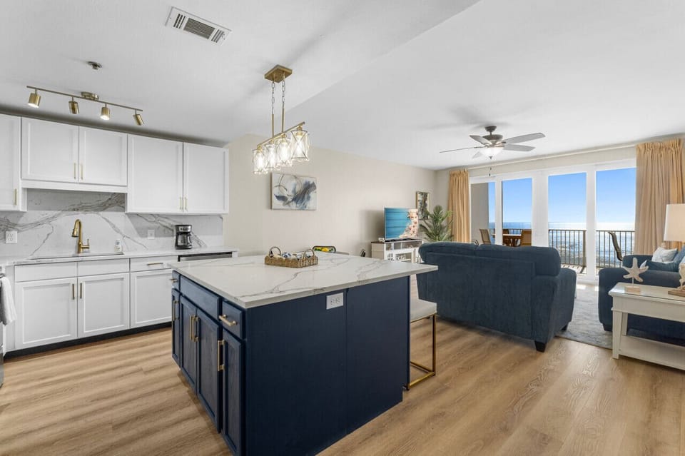 Spacious open-concept living area with a modern kitchen, cozy seating, and stunning ocean views through floor-to-ceiling windows