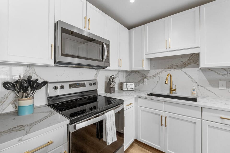 Fully equipped modern kitchen with sleek appliances, marble-style backsplash, and elegant gold accents for a touch of luxury